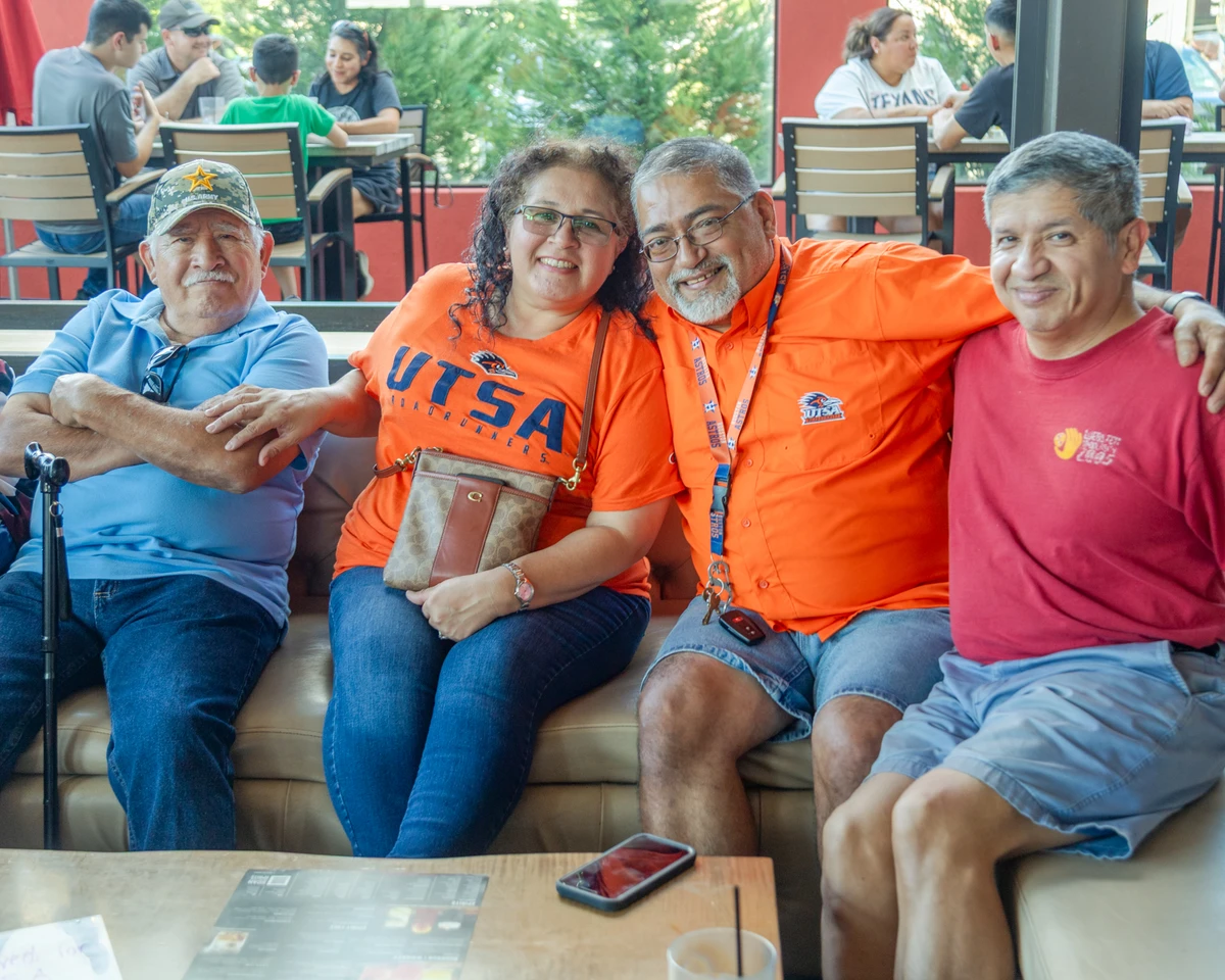 Four people, smiling and posing for a photo in a restraunt.